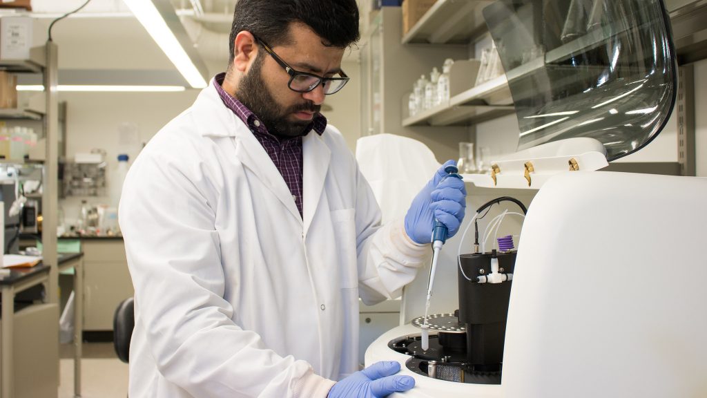 Photo of Jasmeet Lamba water sampling research in a lab, with blue gloves